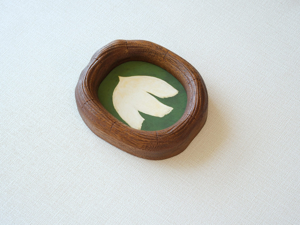 Side perspective of an artisanal wood picture frame showing the natural grain, smooth hand-carved texture, and unique curved silhouette.