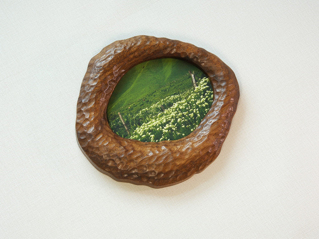 Large walnut wood wall art picture frame with green landscape artwork, high-angle side view.