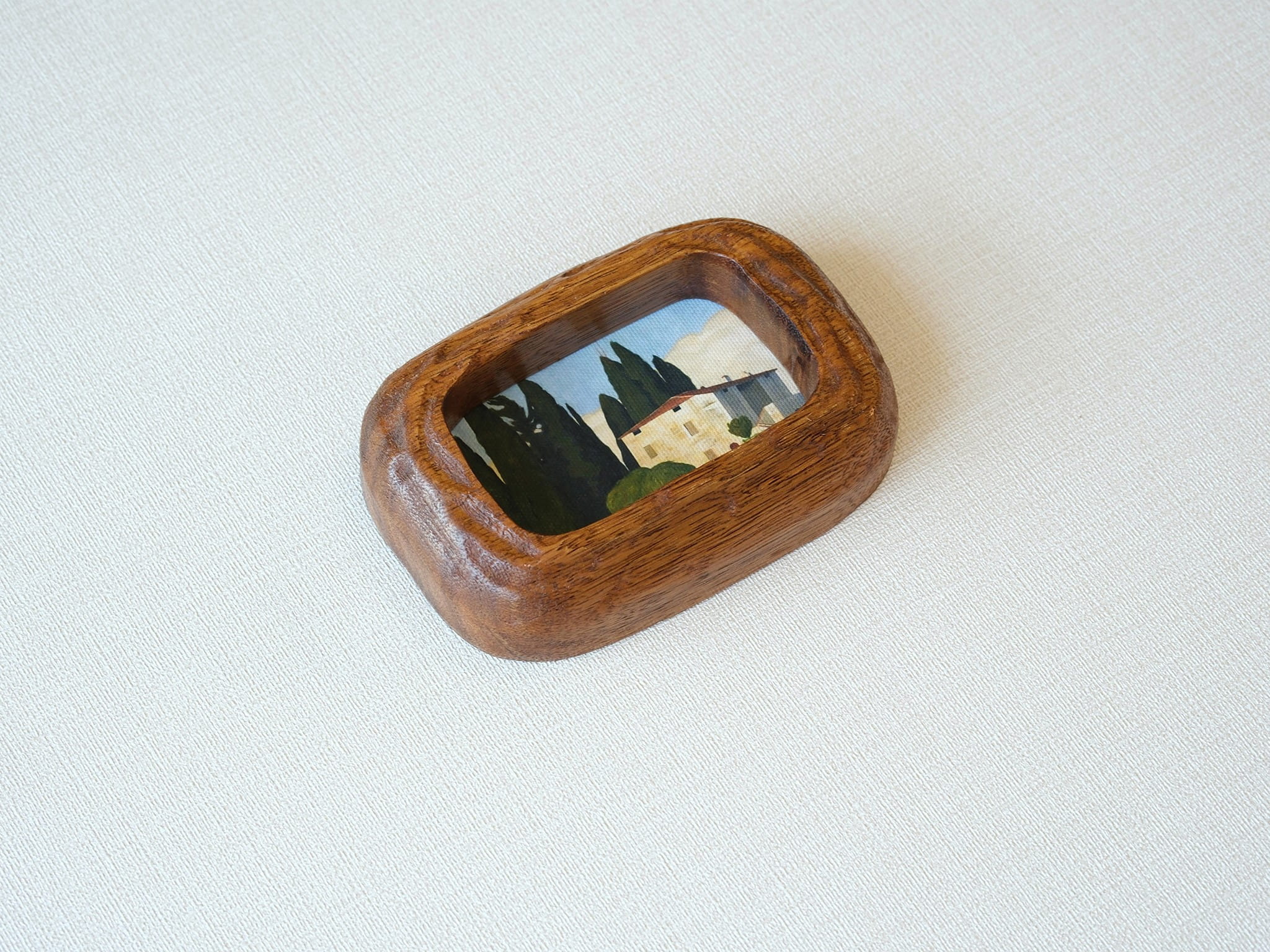 Side angle of a chunky South American walnut frame, showcasing the deep wood texture and handcrafted curved edges.