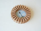 A high-angle view of the sunflower circular solid wood frame lying on a white textured surface, highlighting its natural wood grain.