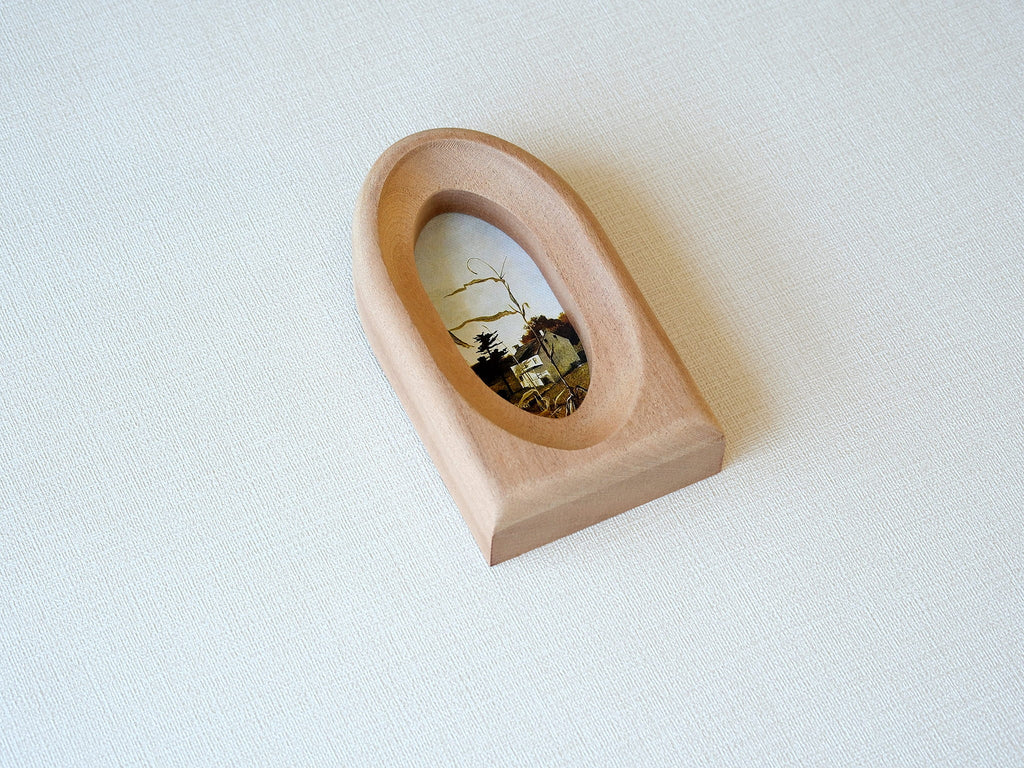 Side angle of the arched wood frame, highlighting its deep portal silhouette and smooth, hand-carved grain details.
