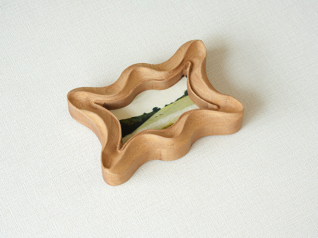 Angled top view of the rippled wave wood frame, highlighting its deep fluid ridges and intricate hand-sculpted texture.