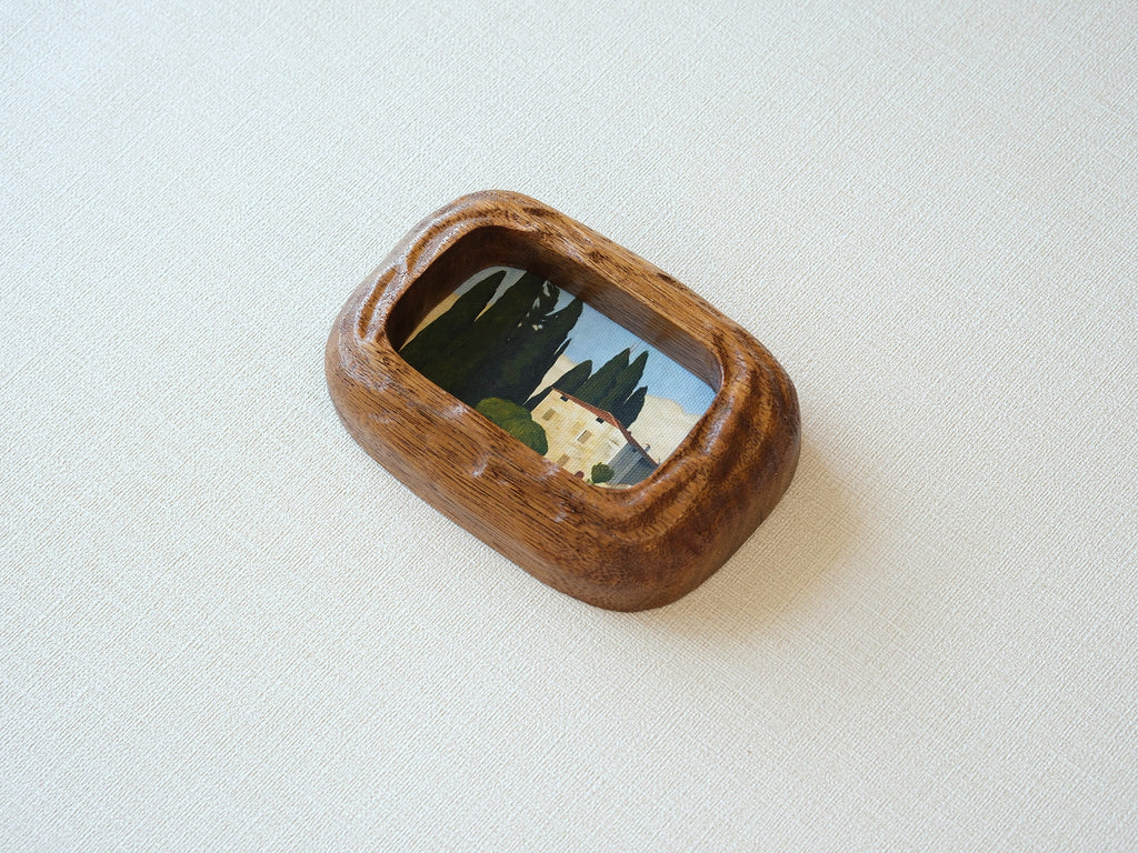 Close-up of a handcrafted walnut frame highlighting the natural wood grain and rustic landscape art print.