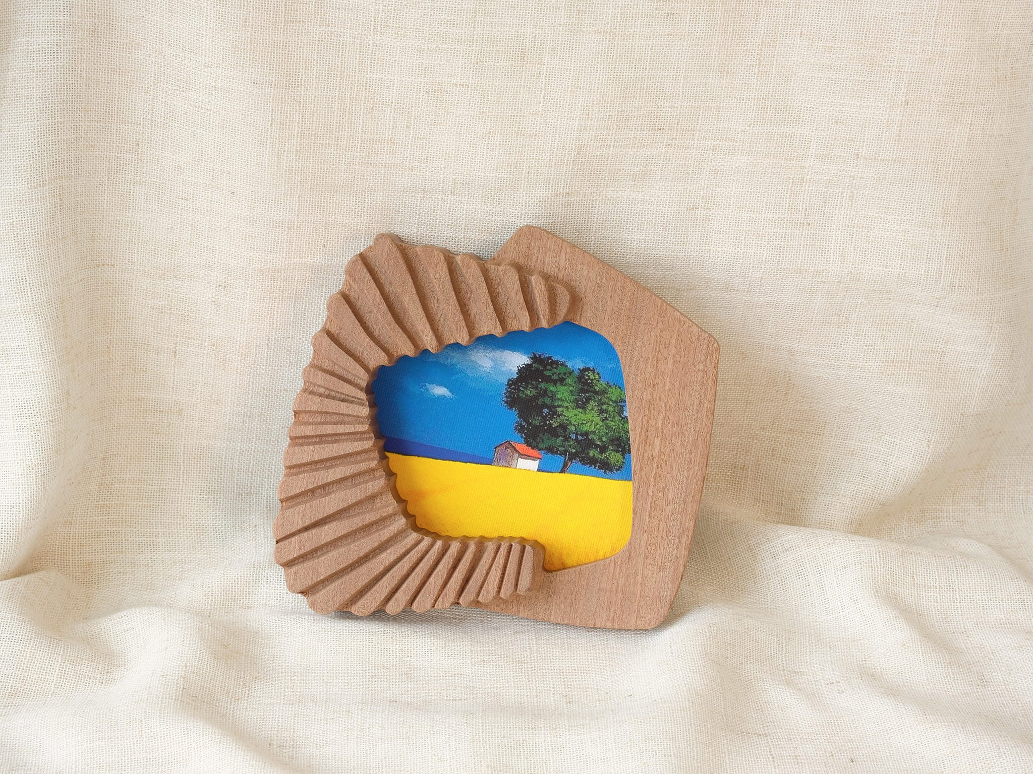 Accordion-inspired handmade solid wood picture frame with colorful landscape artwork, leaning display view.