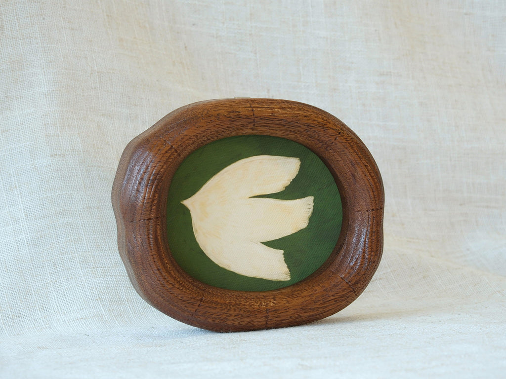 A frontal view of a Fomjia handcrafted wood art frame with a natural organic shape, featuring a cream dove illustration on a green canvas backdrop.