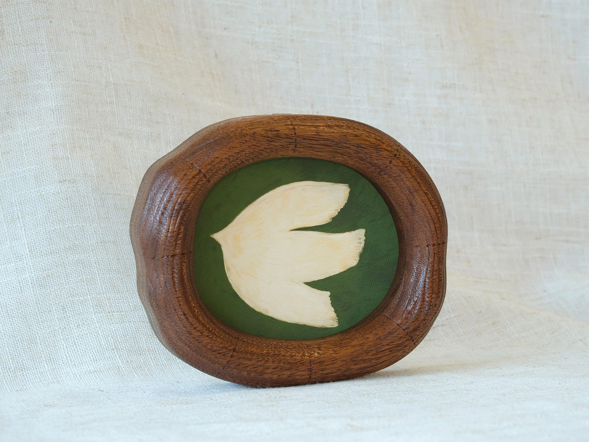 A frontal view of a Fomjia handcrafted wood art frame with a natural organic shape, featuring a cream dove illustration on a green canvas backdrop.