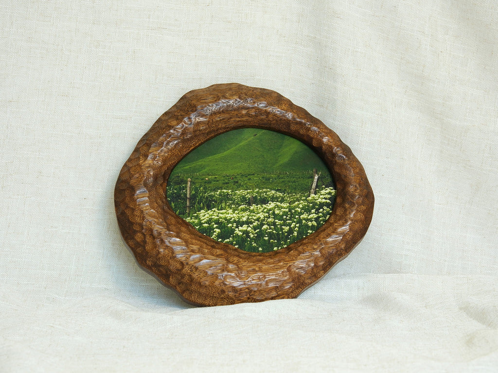 Large walnut wood wall art picture frame with green landscape artwork, leaning display.