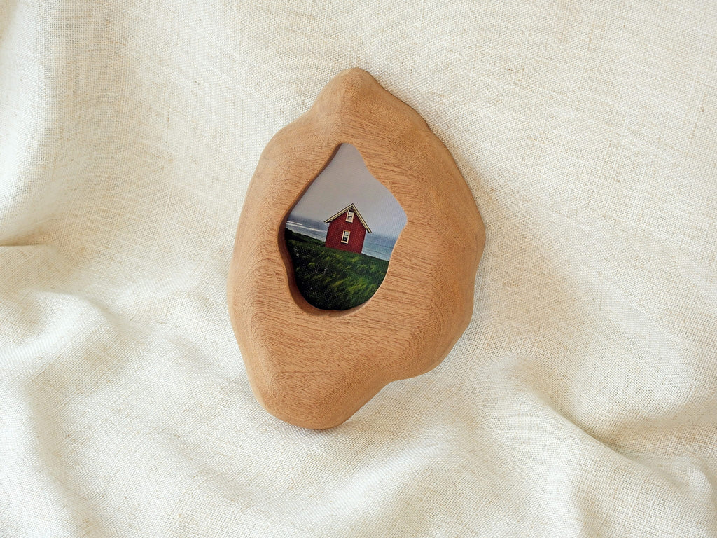 Handmade solid wood wall hanging art picture frame with red house artwork, leaning against the wall.