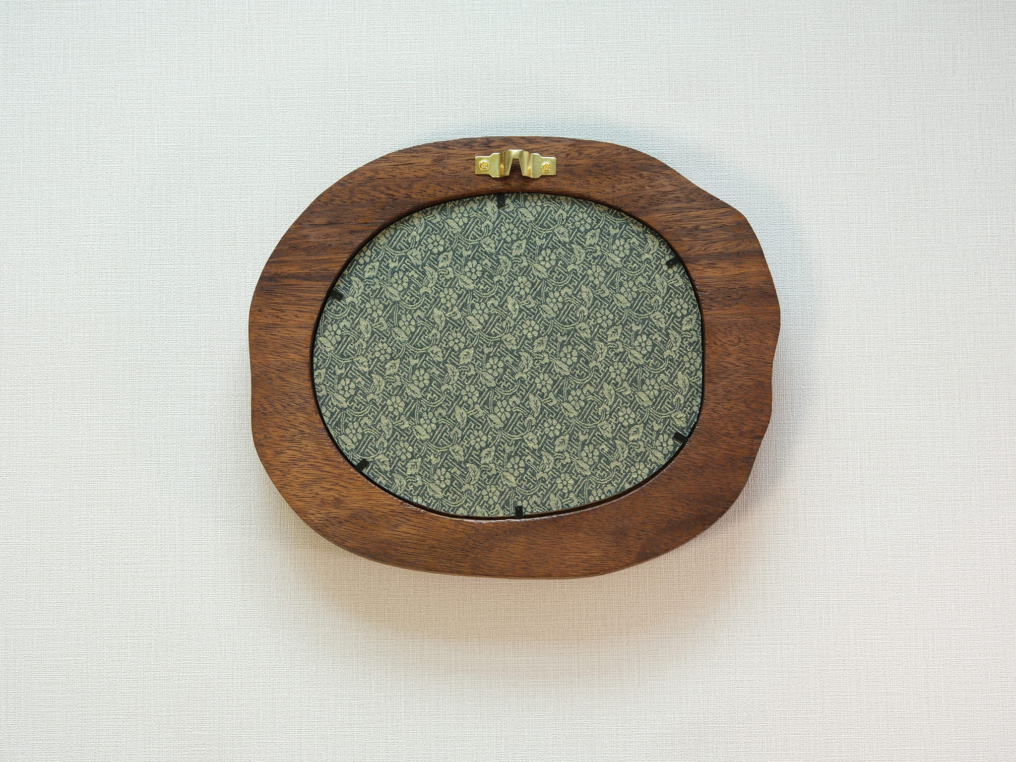 Large walnut wood picture frame back view with wall hanger and patterned backing panel.