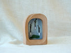 A soft arched wood frame standing firmly on a white textured surface, showcasing its gentle organic silhouette.