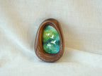 A realistic lifestyle shot of the Waterdrop solid wood frame leaning against a soft white background, displaying the vibrant colors of the flying birds and the rich, dark tones of the natural wood.