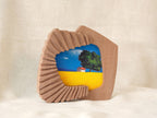 Accordion-inspired handmade solid wood picture frame with colorful landscape artwork, standing display view.