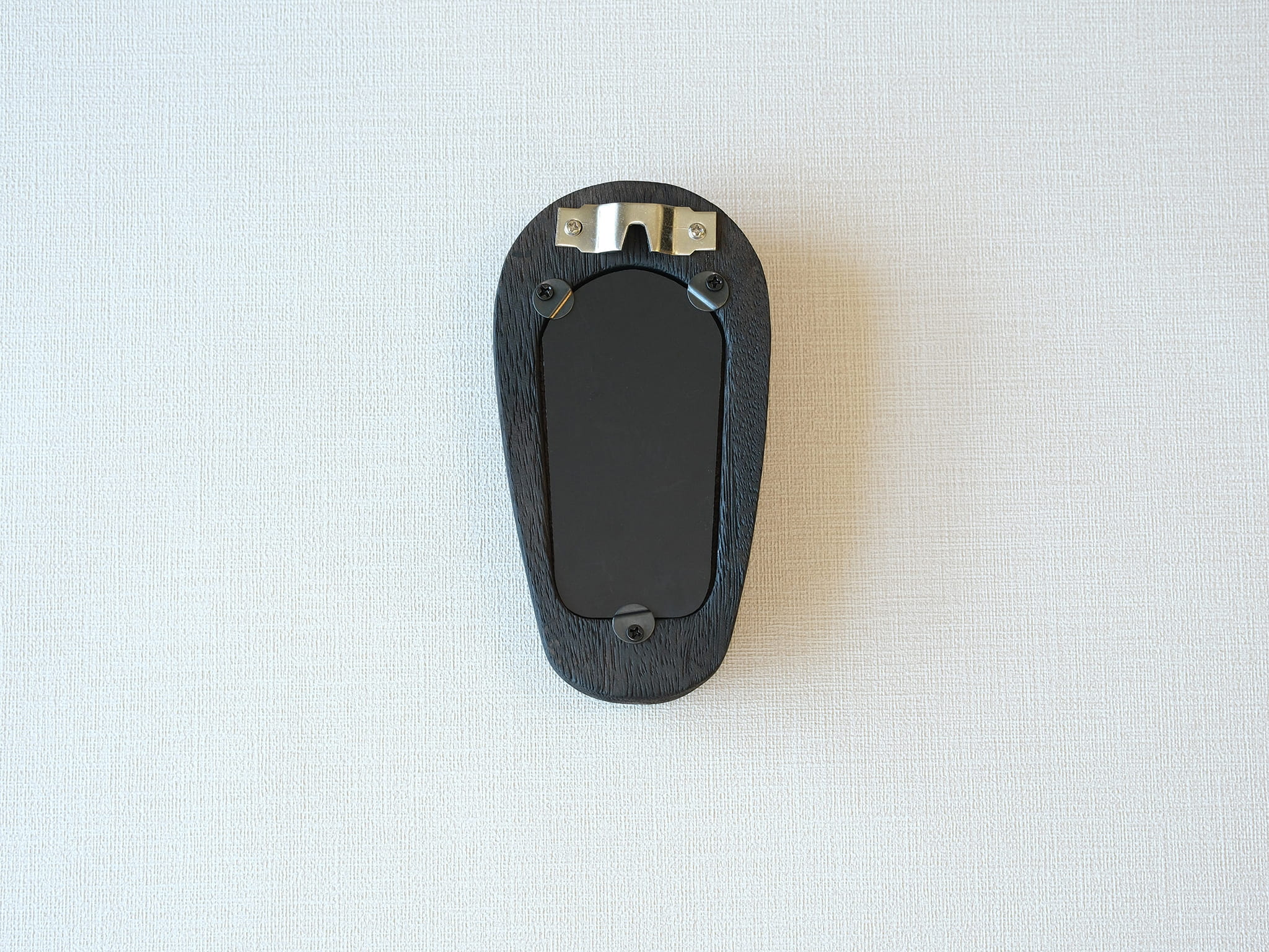 Back view of the black arched frame, featuring an integrated metal wall hanger and three secure swivel tabs.