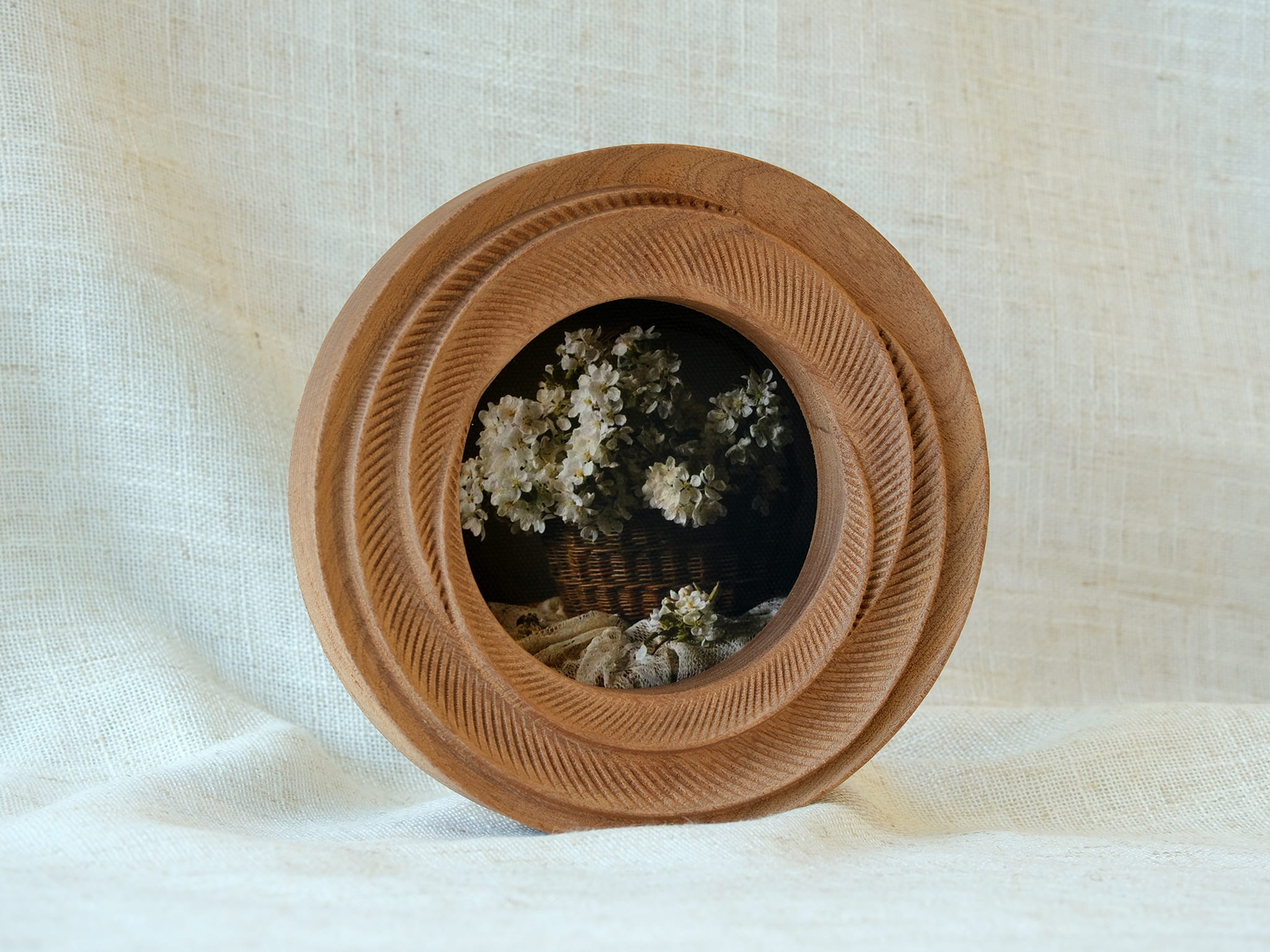 Side view of the round flower frame standing upright, showcasing its thick tiered profile and hand-carved details.