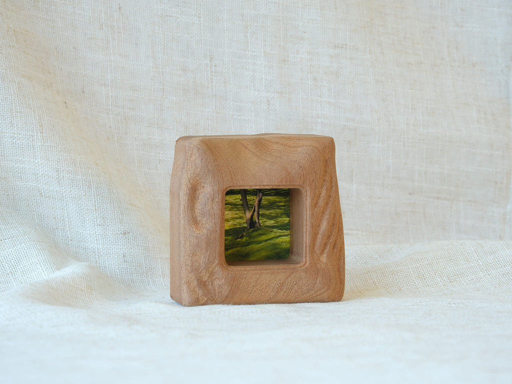 A front-perspective view of the handmade mini square frame standing upright on a white textured surface. The image highlights the frame's stable, thick base and the intricate "Moderno Organico" hand-carved wavy details on the side, creating a sculptural desktop art piece.