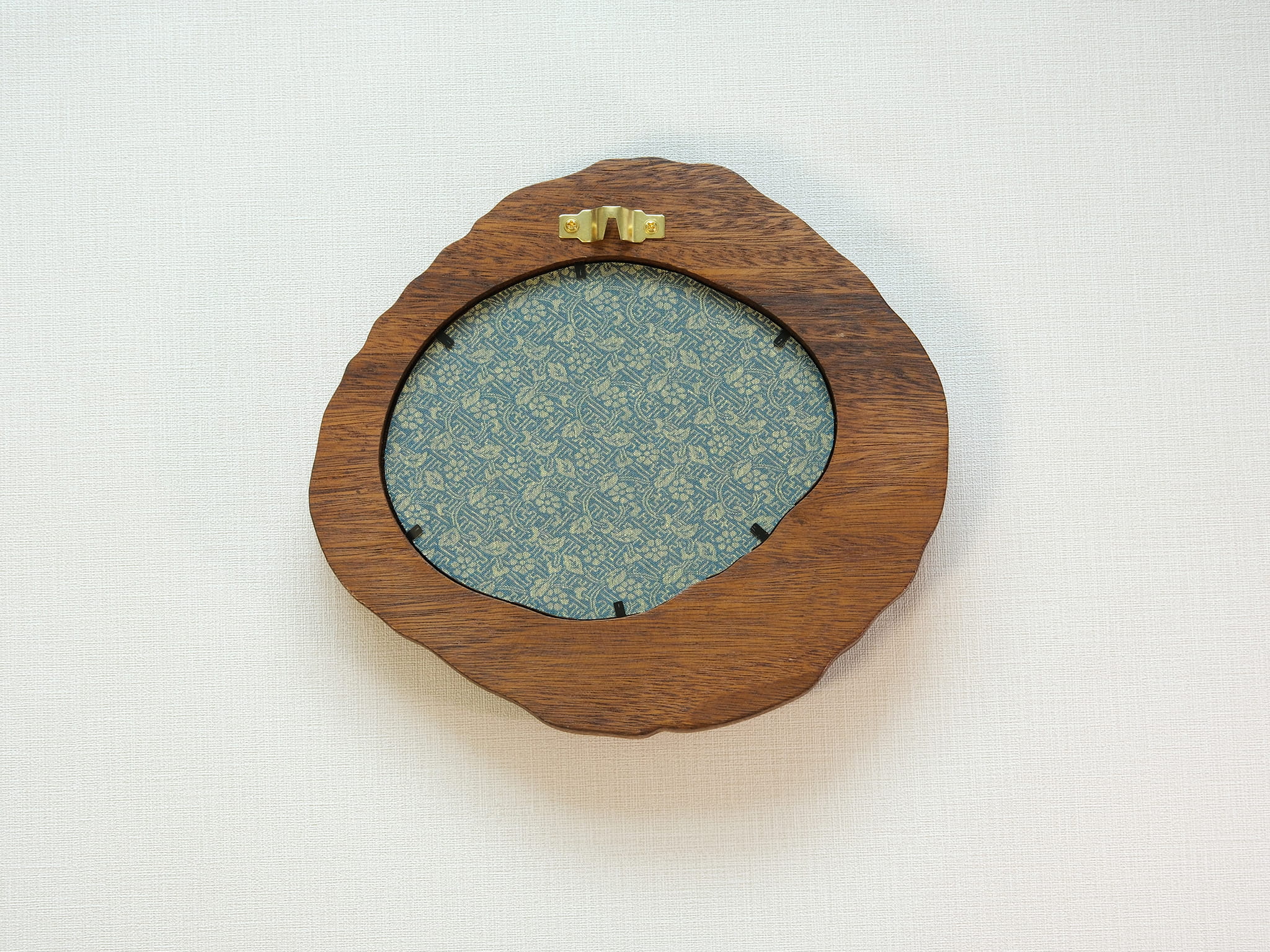 Large walnut wood picture frame back view with wall hanger and patterned backing panel.