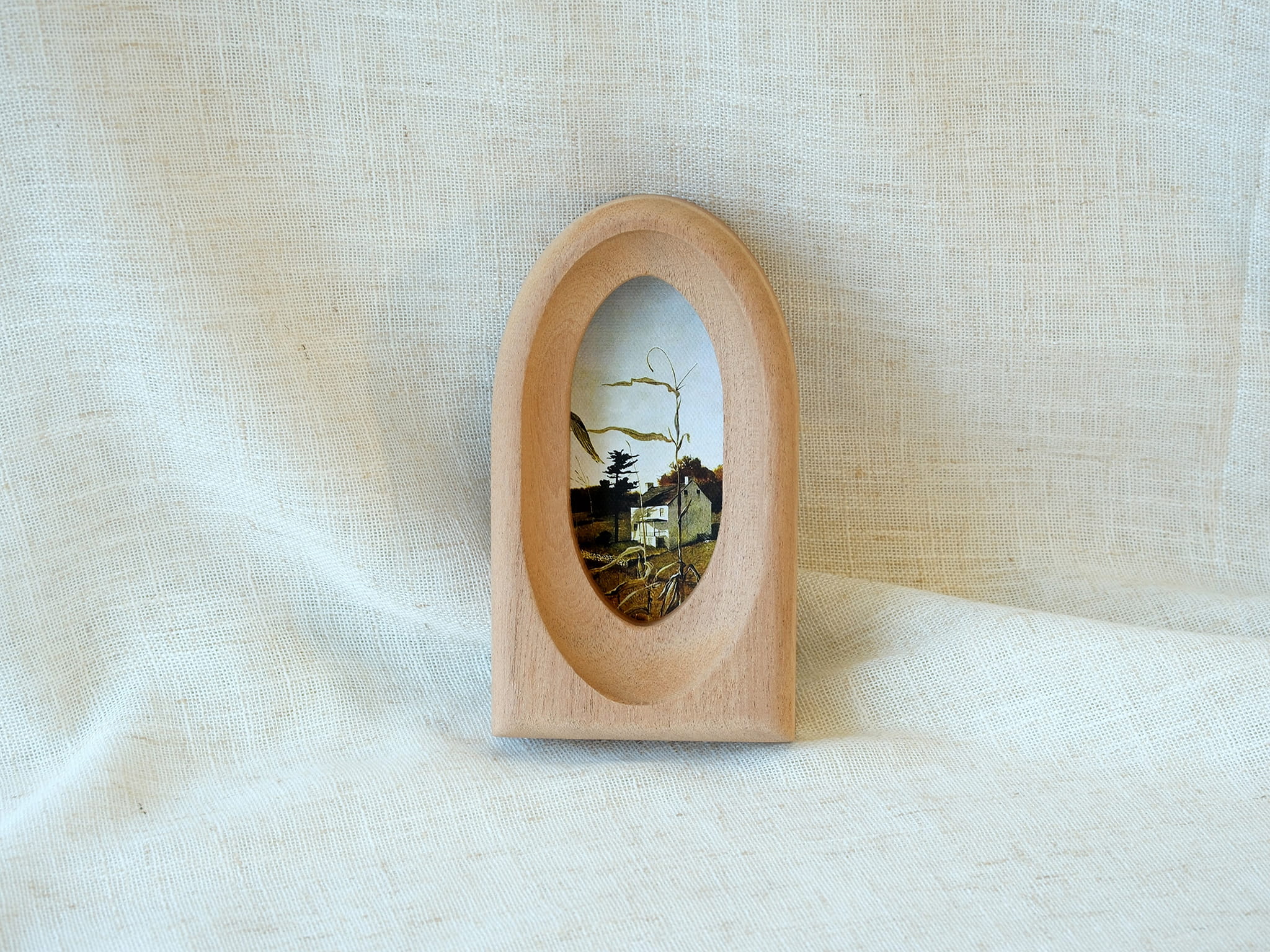 Arched wood art frame leaning against a wall, showcasing its graceful portal silhouette and warm, natural aesthetic.
