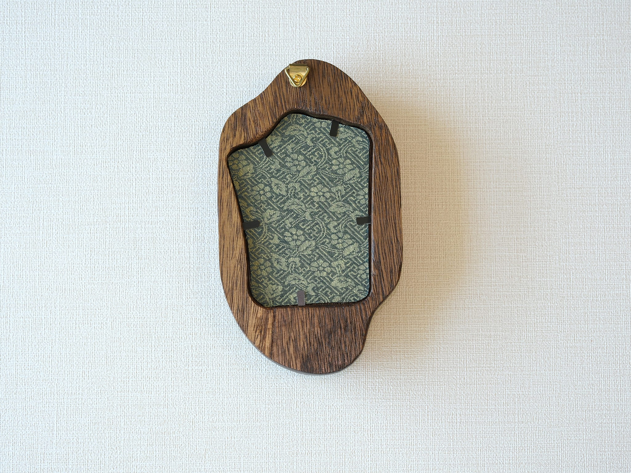 Rear view of the irregular organic solid wood frame, showing the integrated gold wall hanger and the patterned fabric backing that secures the artwork.