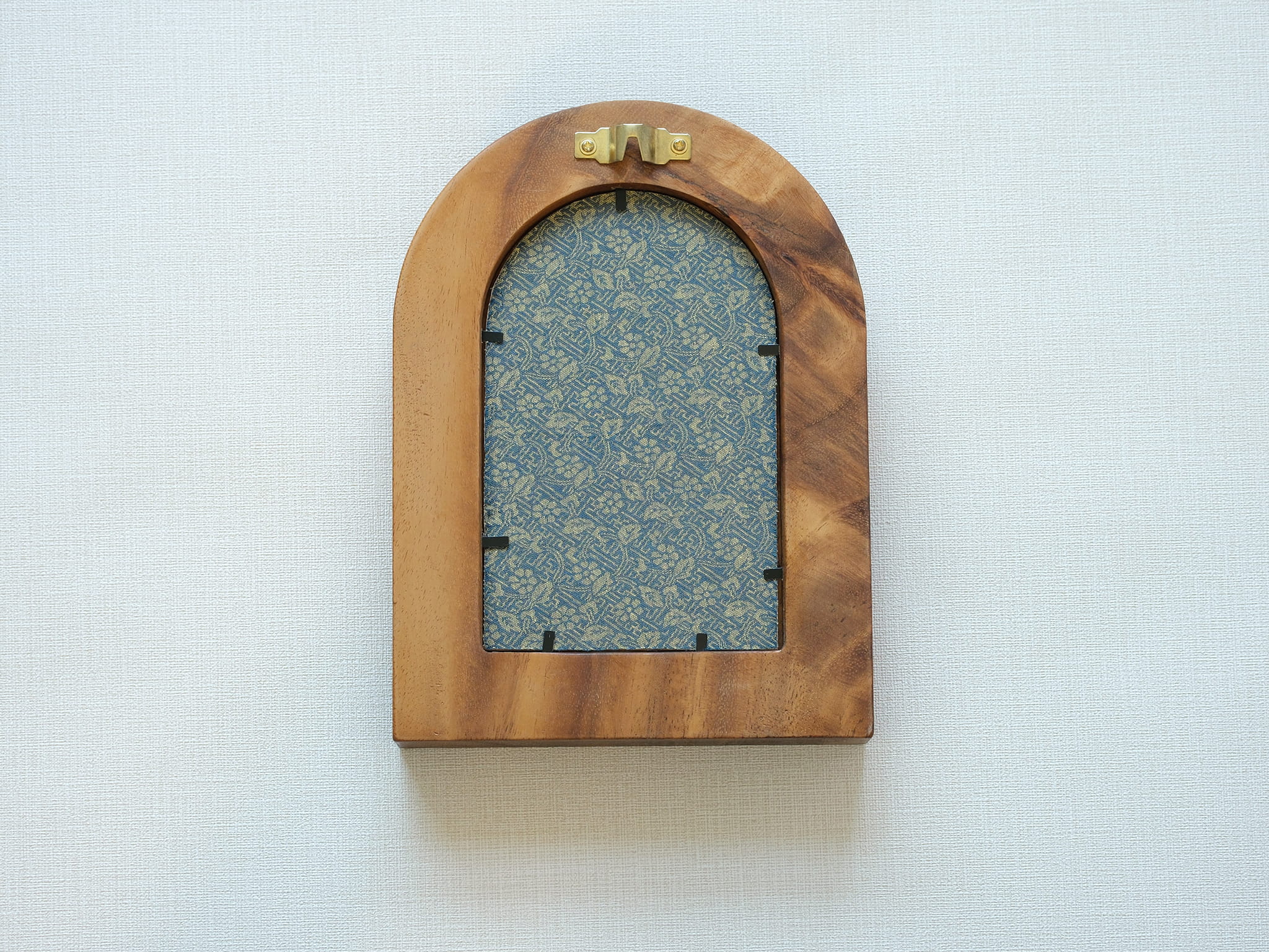 Rear view of the arched "Tuscany" solid wood frame, showing the integrated gold wall hanger and the elegant blue and gold floral textile backing that protects the artwork.