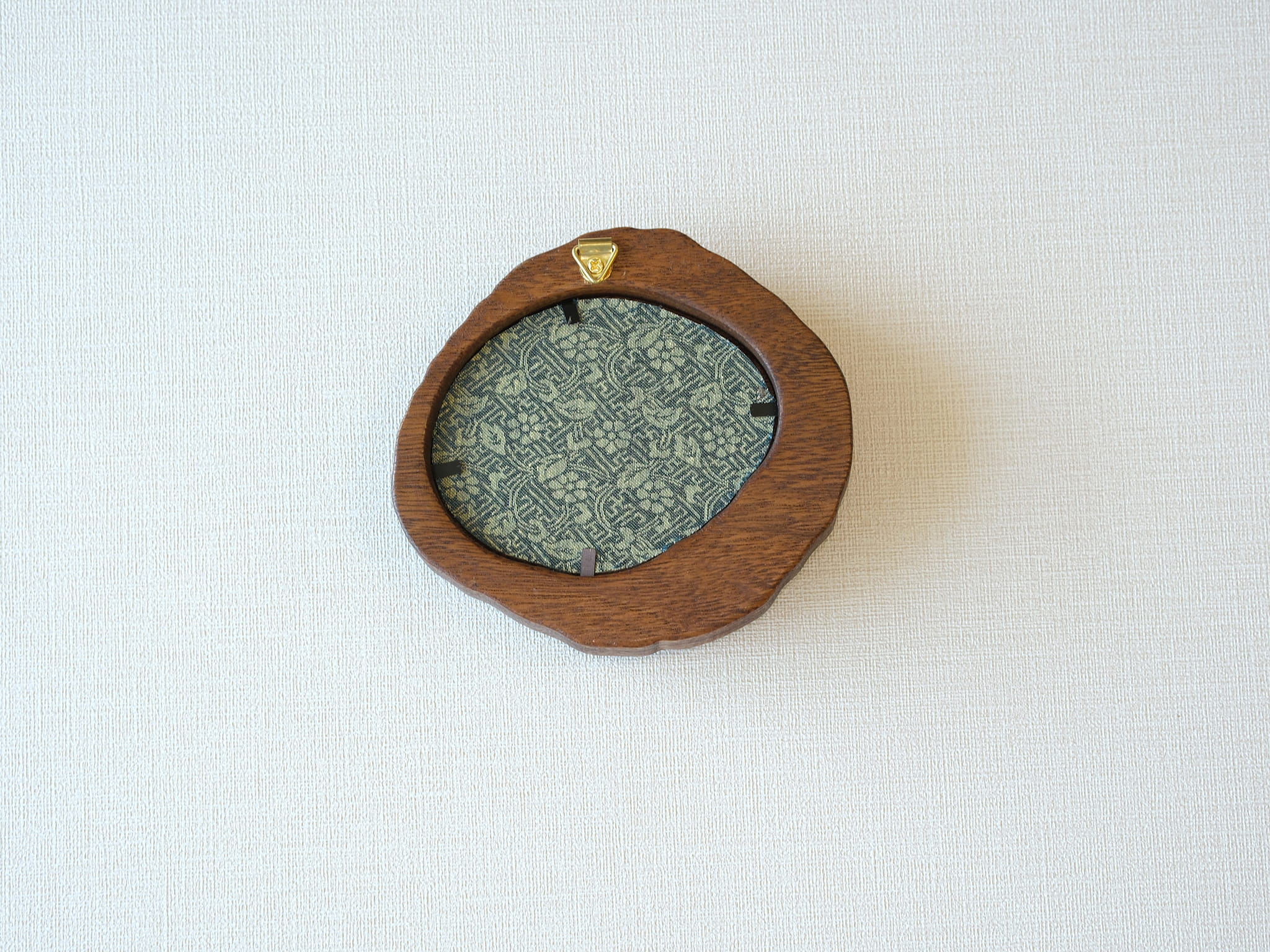 Rear view of the lake-shaped organic solid wood frame, revealing the uniquely patterned blue and gold textile backing and the integrated gold wall hanger.