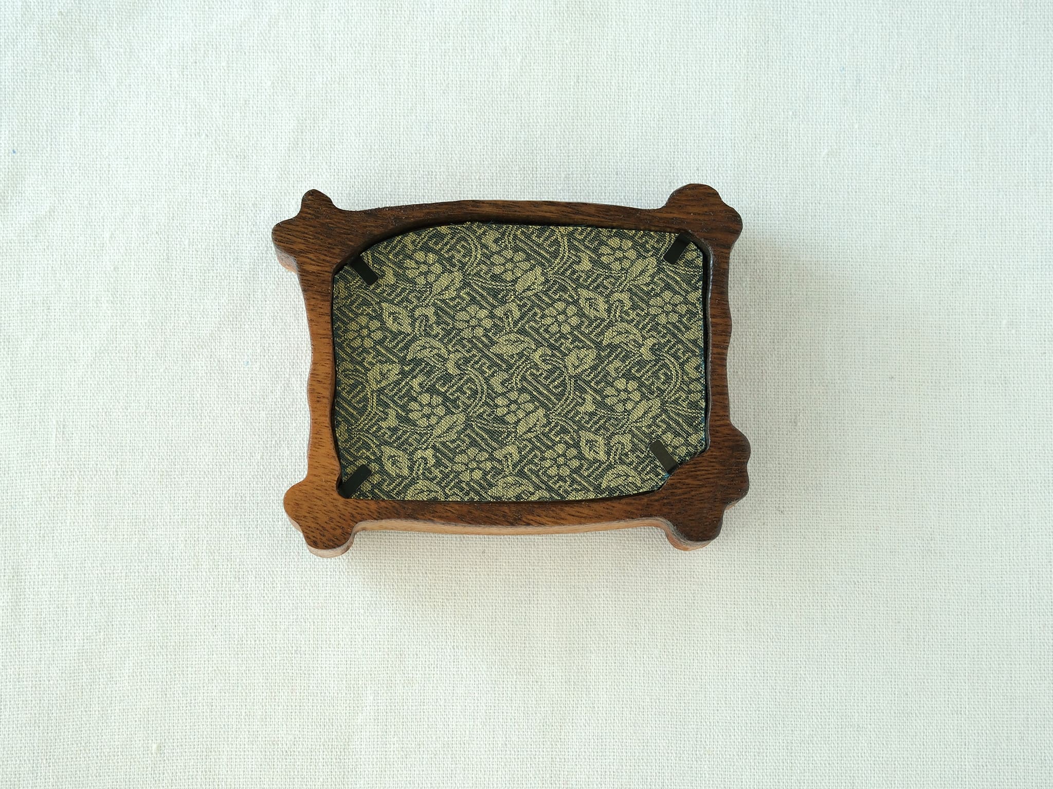 Rear view of the handcrafted nature-inspired wood frame featuring a green floral fabric backing, secure metal fasteners, and a golden hanging hook.