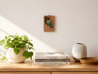 Handmade solid wood wall hanging art frame displayed in a warm home interior with books, candles, and green plants.