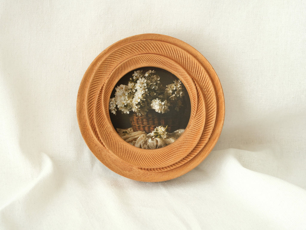The round flower frame leaning against white fabric, showcasing its radiant tiered textures as artistic desktop decor.