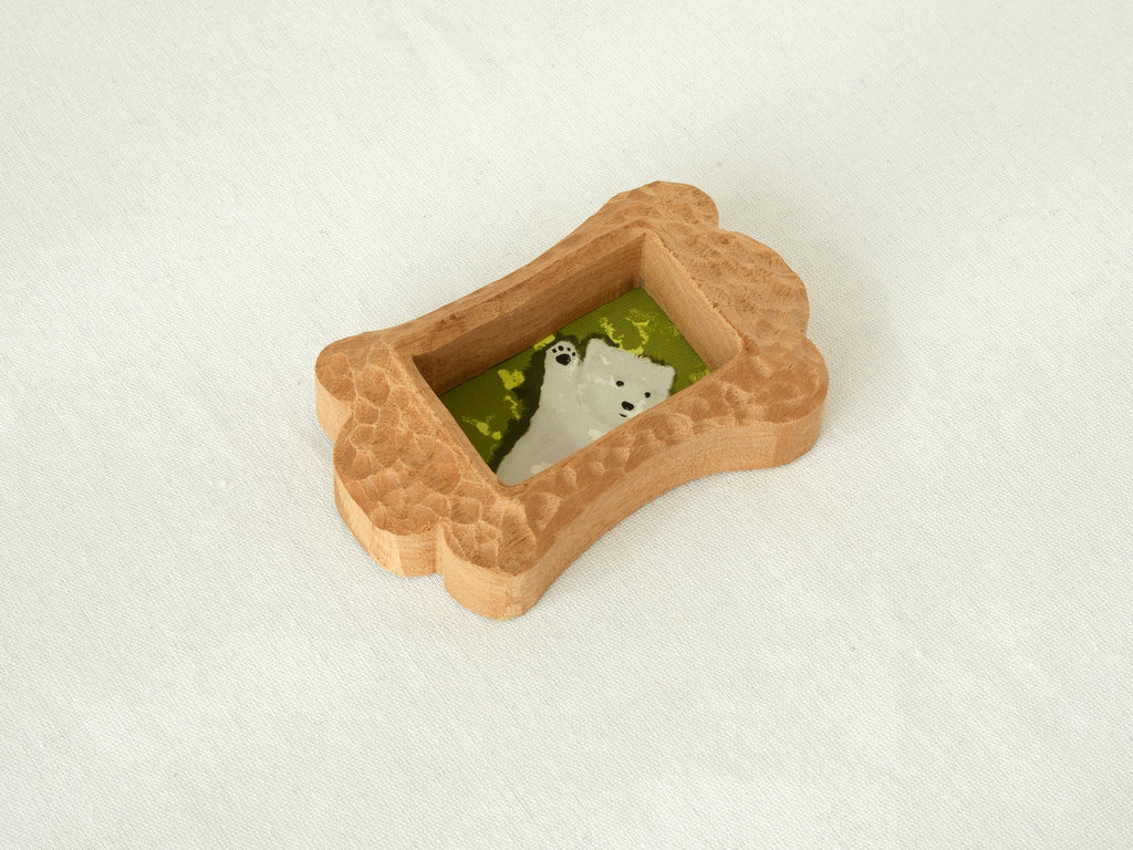 Top-down angled view of the bone-shaped pet frame, highlighting the deep hand-chiselled texture and thick solid wood profile.