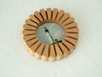 A high-angle view of the sunflower circular solid wood frame lying on a white textured surface, highlighting its natural wood grain.