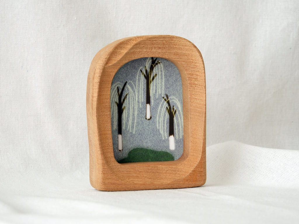 A soft arched wood frame standing firmly on a white textured surface, showcasing its gentle organic silhouette.
