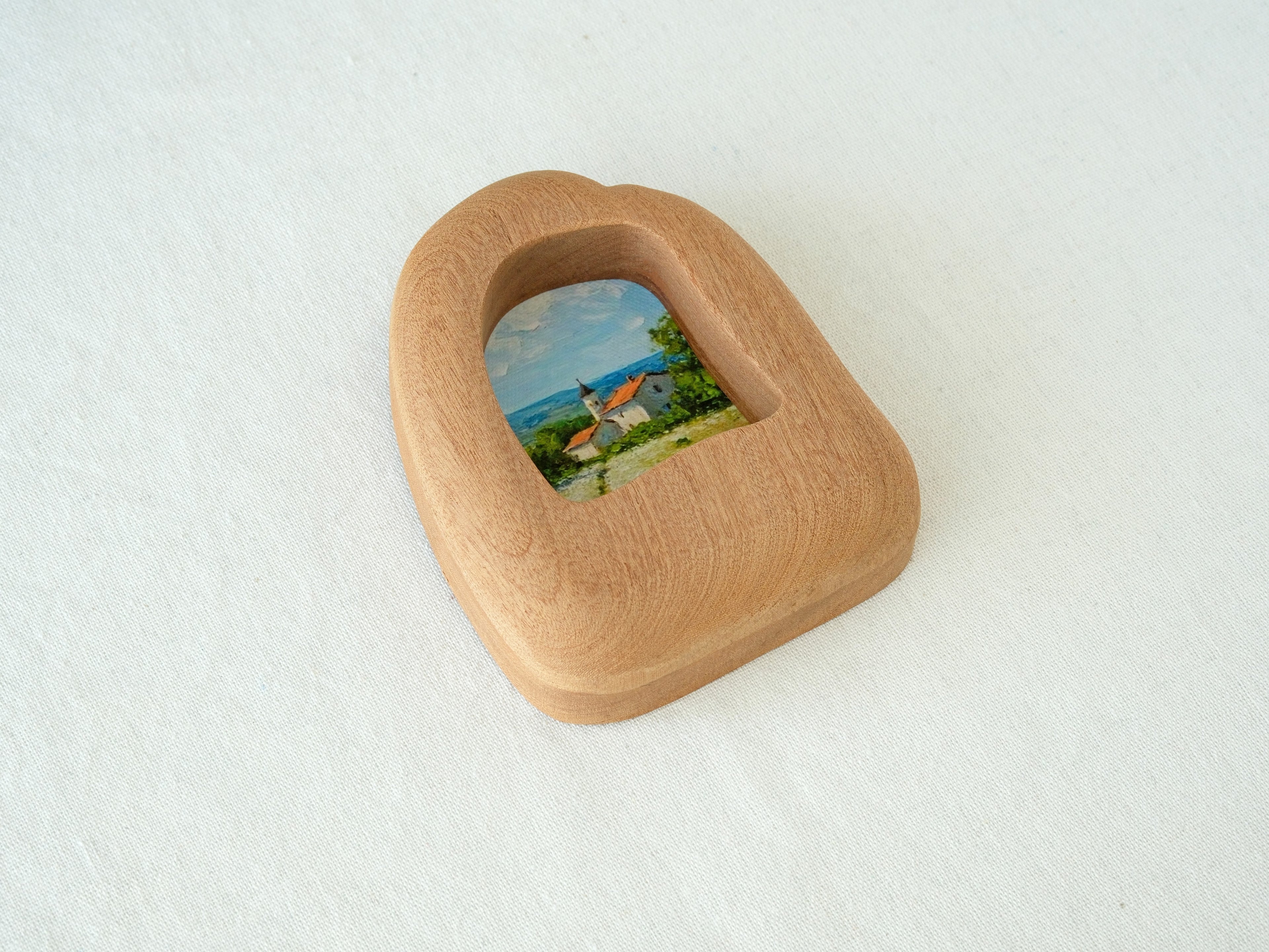 Alternative side angle of the house-shaped frame, showcasing the unique undulating texture and rich natural wood grain.