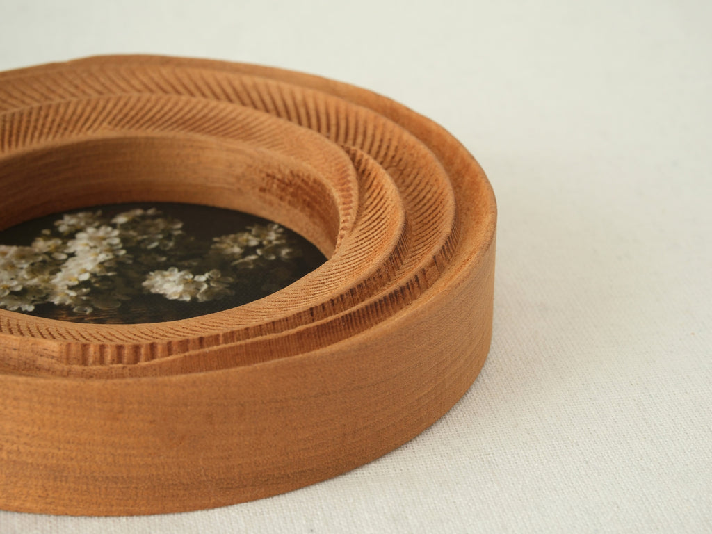 Close-up of the round flower frame, showing the intricate hand-carved textures and its unique three-tier stepped profile.