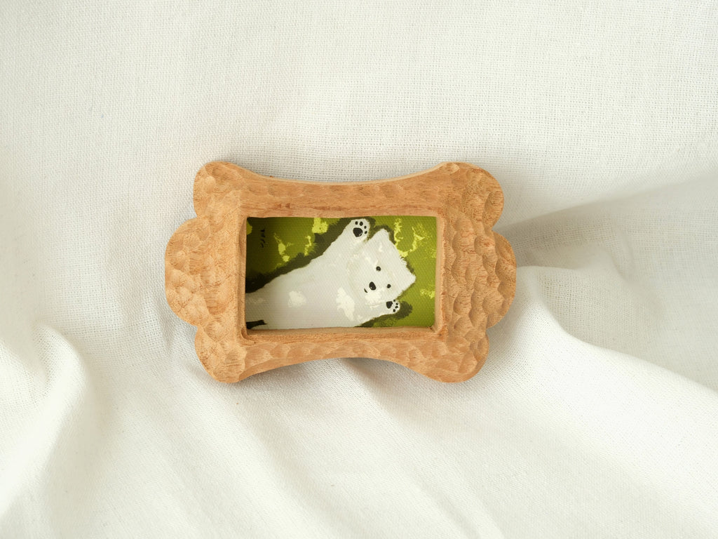 The bone-shaped wood frame leaning against a soft fabric backdrop, showcasing its artistic handcrafted charm as desktop decor.