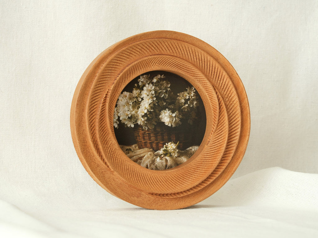 Side view of the round flower frame standing upright, showcasing its thick tiered profile and hand-carved details.