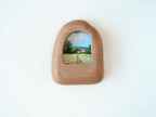 House-shaped wood frame leaning against a soft white textured wall, creating a cozy and natural aesthetic.