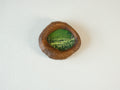 Front view of the lake-shaped organic solid wood frame, featuring a serene landscape painting of a green meadow filled with white wildflowers.