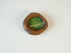 Front view of the lake-shaped organic solid wood frame, featuring a serene landscape painting of a green meadow filled with white wildflowers.