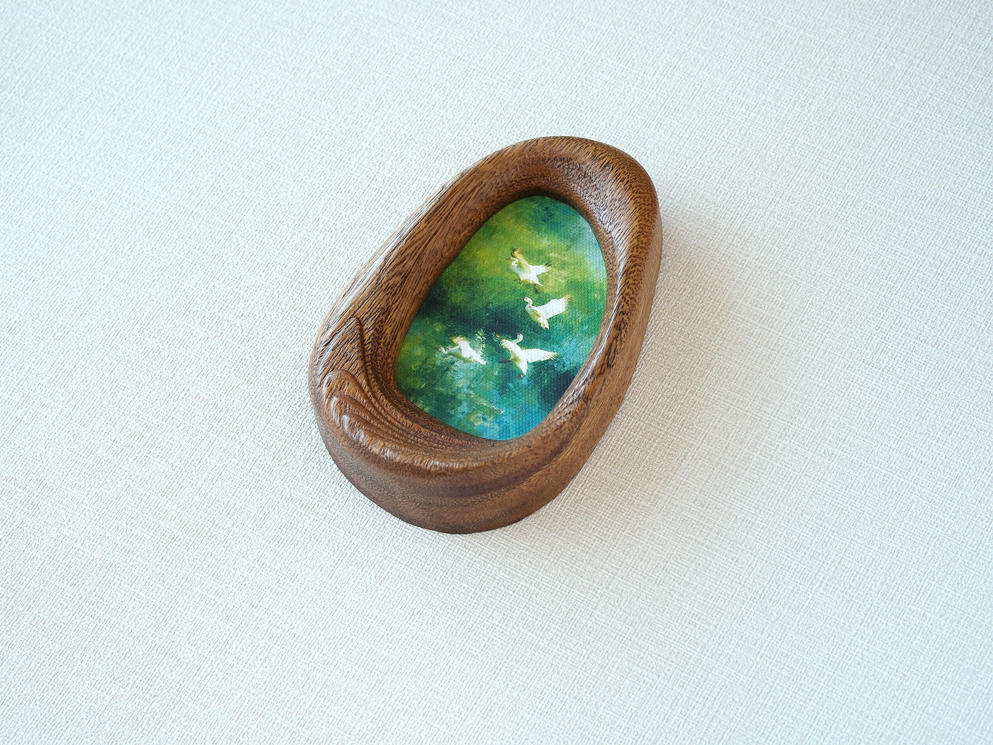 Side view of the Waterdrop handmade solid wood art frame, showcasing the thick pebble-like profile, smooth hand-polished edges, and the depth of the forest birds artwork.