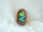 A realistic lifestyle shot of the Waterdrop solid wood frame leaning against a soft white background, displaying the vibrant colors of the flying birds and the rich, dark tones of the natural wood.