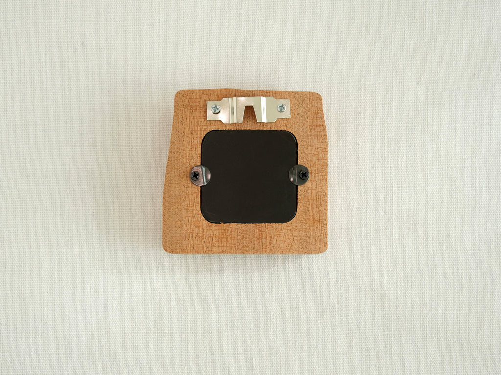 The back view of the mini solid wood frame, showing a silver metal sawtooth hanger for wall mounting and a black backing secured by two turn buttons. The natural grain and clean finish of the Sapele wood are visible on the reverse side.
