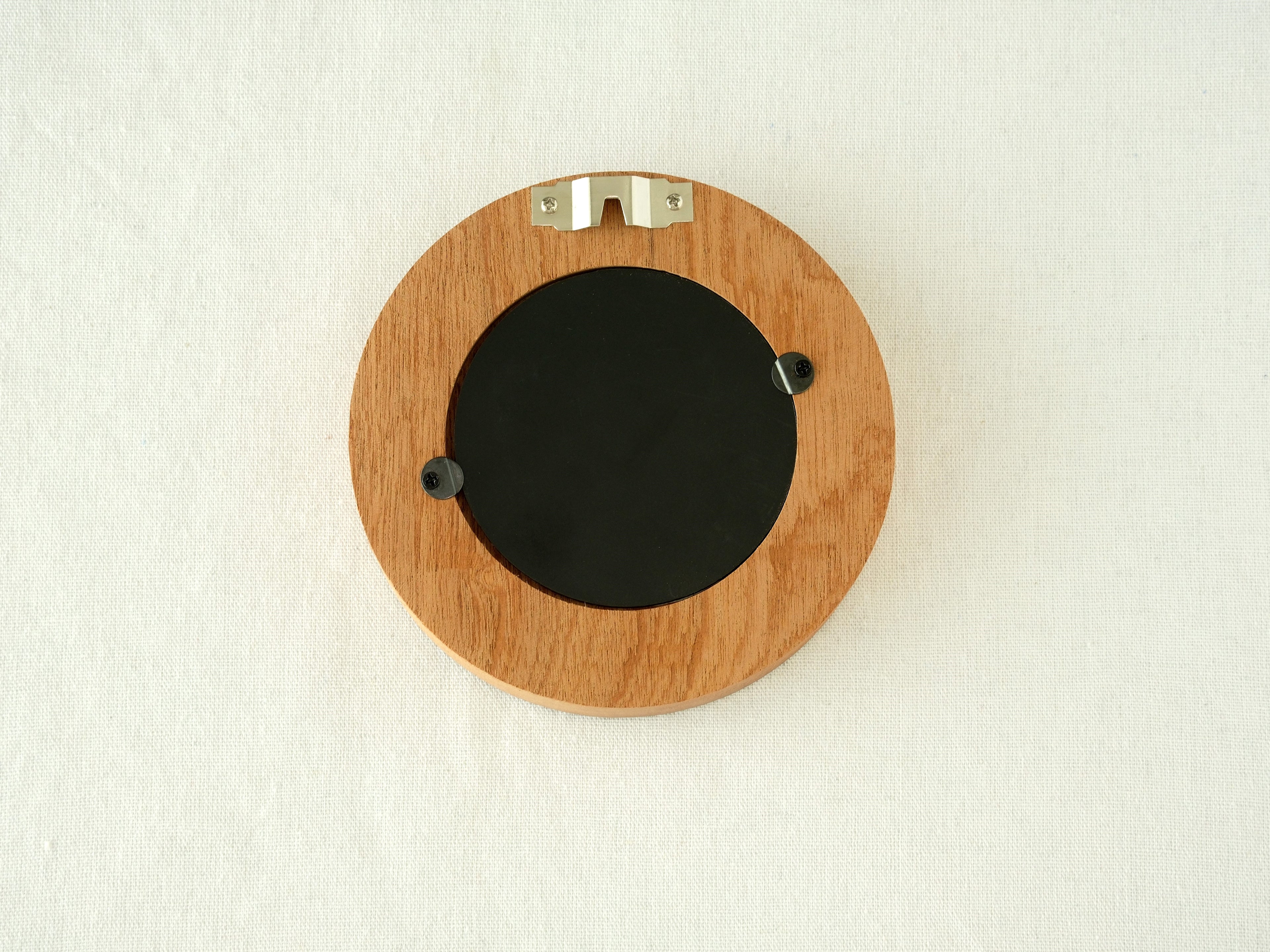 Back view of the round flower frame, showing the sturdy wood finish, three swivel tabs, and integrated wall hanger.