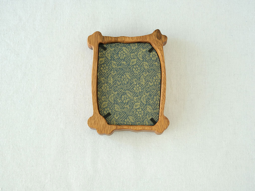 Back view of the organic solid wood frame, showing the elegant green patterned backing fabric and black metal retainer clips.