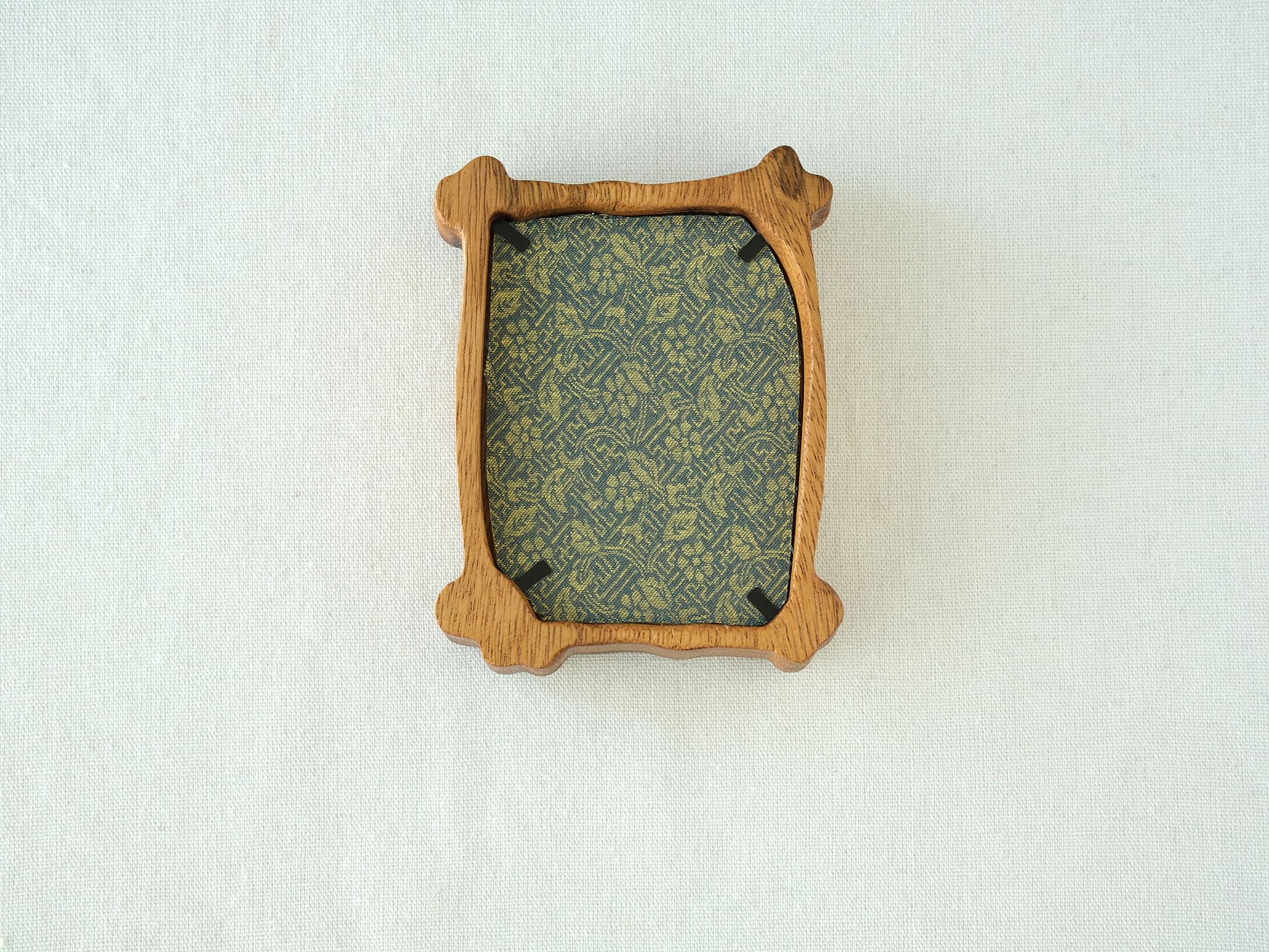 Back view of the organic solid wood frame, showing the elegant green patterned backing fabric and black metal retainer clips.