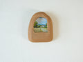 House-shaped wood frame leaning against a soft white textured wall, creating a cozy and natural aesthetic.