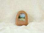 Front view of a house-shaped wood frame, featuring a hand-carved organic silhouette and warm Sapele grain.