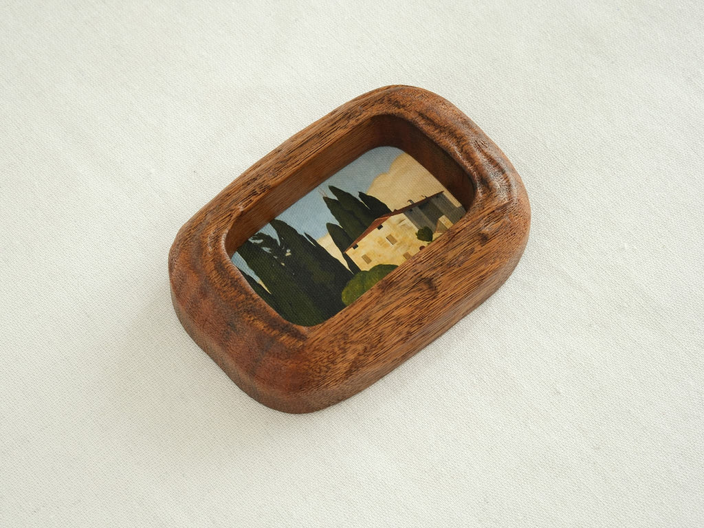 Side angle of a chunky South American walnut frame, showcasing the deep wood texture and handcrafted curved edges.