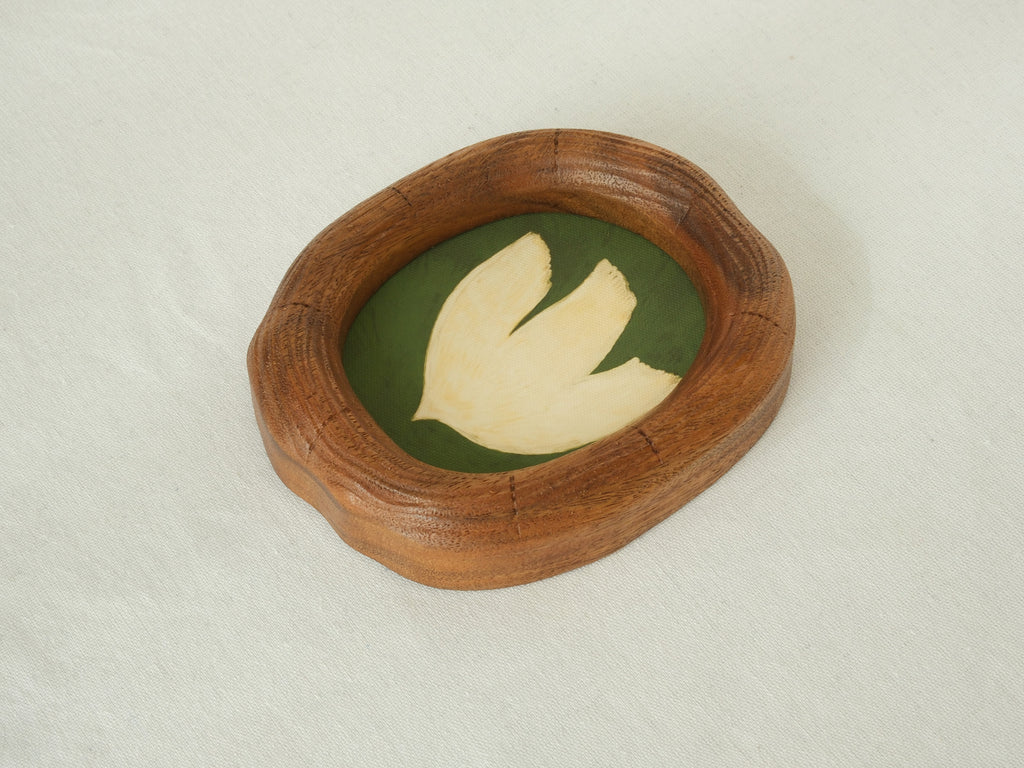 Side perspective of an artisanal wood picture frame showing the natural grain, smooth hand-carved texture, and unique curved silhouette.