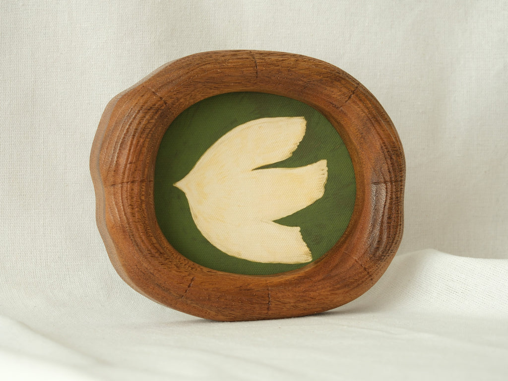A frontal view of a Fomjia handcrafted wood art frame with a natural organic shape, featuring a cream dove illustration on a green canvas backdrop.