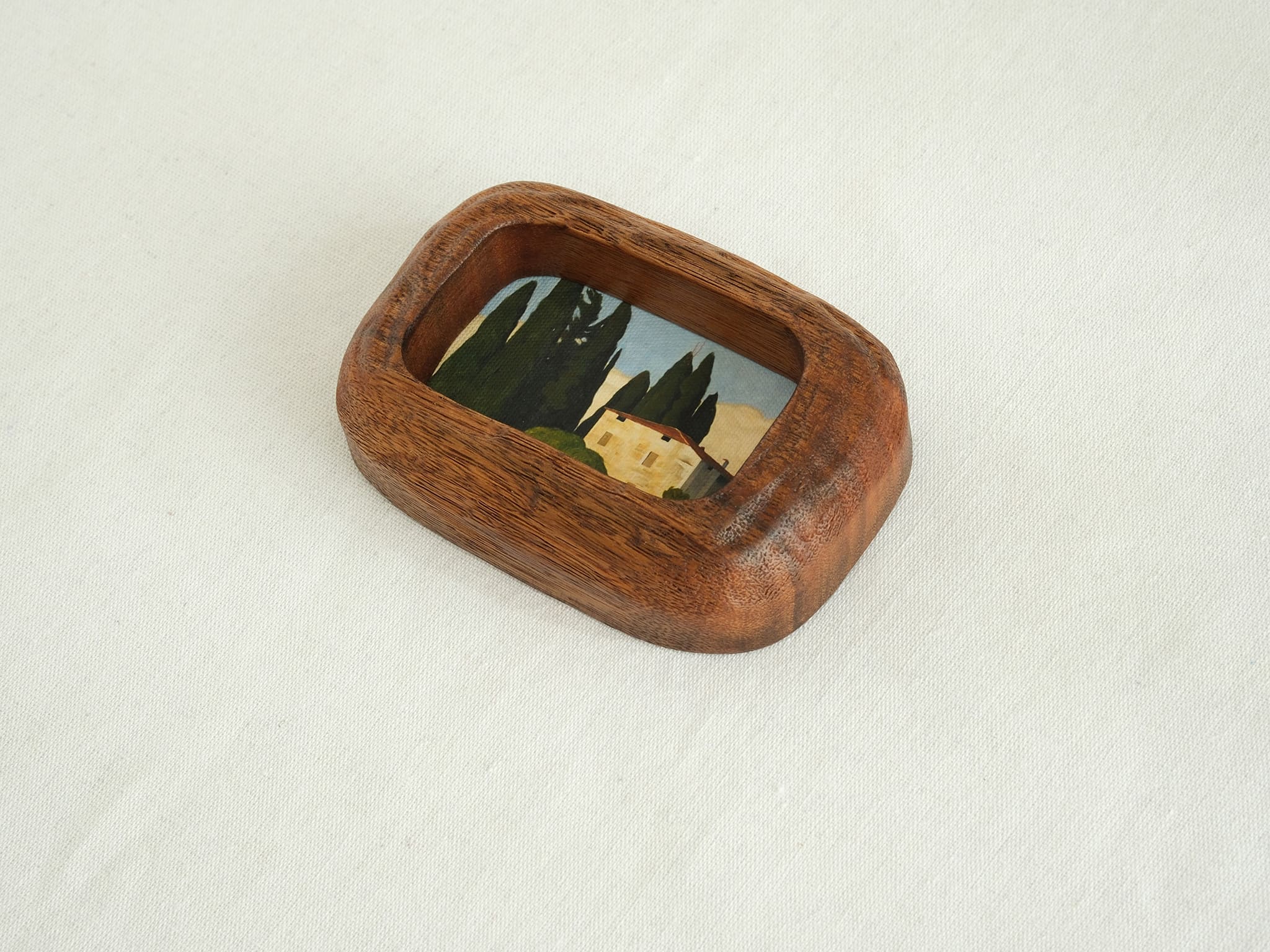 Close-up of a handcrafted walnut frame highlighting the natural wood grain and rustic landscape art print.